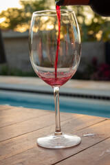 A crystal glass next to a sink while wine is being poured into it.