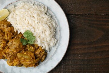 Delicious chicken curry with rice on wooden table, top view