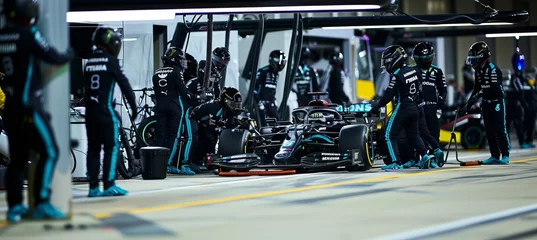  Formula 1 racing car undergoing maintenance and pit stop with the technical team assisting. © Ilja