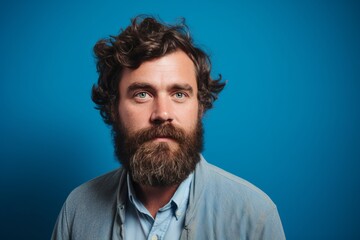 Portrait of a handsome bearded man looking at camera on blue background