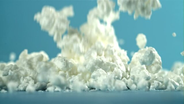 Fresh cottage cheese falling on blue background. Filmed on a high-speed camera at 1000 fps. High quality FullHD footage