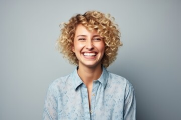 Portrait of a happy young woman with curly hair over grey background