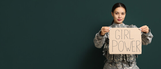 Young female soldier holding paper with slogan GRL PWR on dark background with space for text....