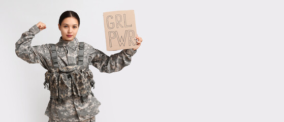 Young female soldier holding paper with slogan GRL PWR on white background with space for text....