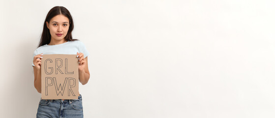 Young woman holding paper with slogan GRL PWR on white background with space for text. Feminism...