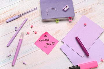 Sticky note with text THANK YOU and stationery on grunge background