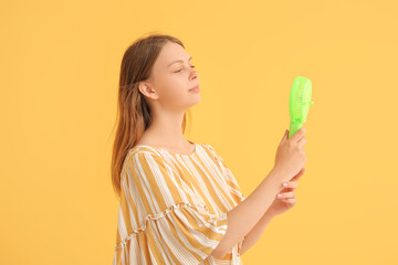 Beautiful young woman with handheld mini fan on yellow background © Pixel-Shot