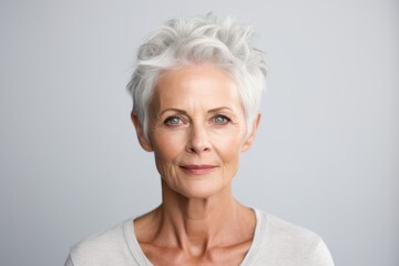 Portrait of beautiful senior woman with grey hair against grey background.