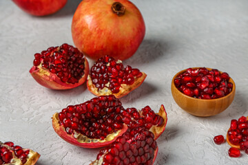 Fresh pomegranates and bowl with seeds on white background