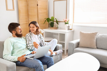 Happy couple in love using laptop on sofa at home