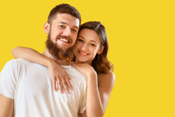 Happy couple in love hugging on yellow background