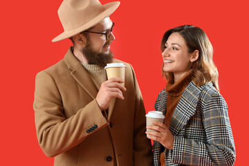 Happy couple in love with cups of coffee on red background