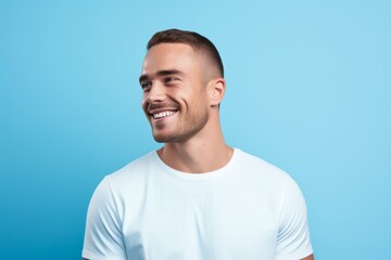 Portrait of happy young man in white t-shirt on blue background