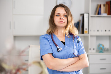 Portrait of female doctor who is working and posing on her workplace in the clinic.