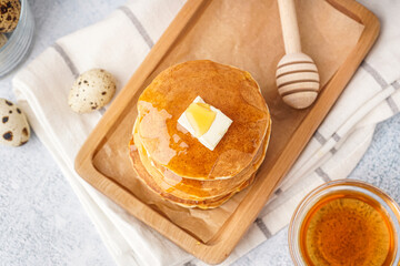 Wooden board of tasty pancakes with butter and maple syrup on white background