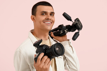 Obraz premium Male photographer with modern camera and tripod on pink background