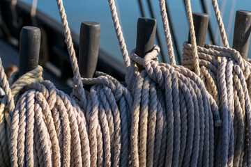The early morning light gently illuminates the coiled ropes and wooden belaying pins of a classic...