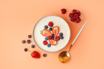 Bowl of tasty semolina porridge with fresh berries on orange background