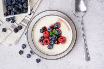 Bowl of tasty semolina porridge with fresh berries on white background