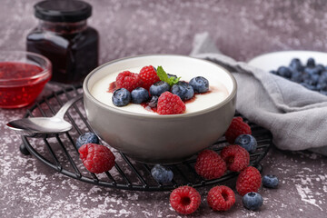 Bowl of tasty semolina porridge with fresh berries on grey background