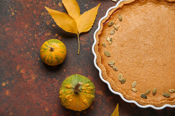 Baking dish with tasty pumpkin pie on brown background