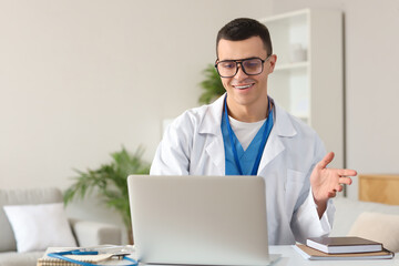 Young doctor video chatting with patient on laptop at home