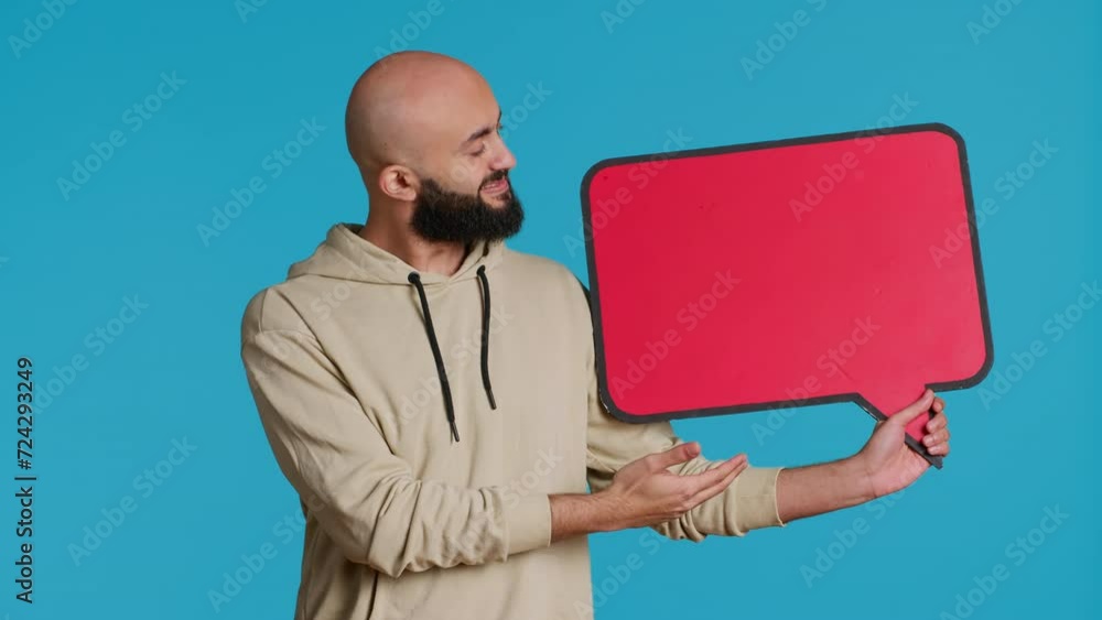 Poster arab person holding red speech bubble icon in studio, creating web advertisement for new product com
