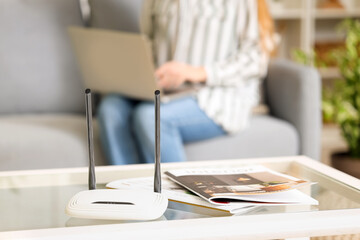 Modern wi-fi router and magazines on table in living room, closeup