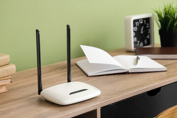 Modern wi-fi router on table near green wall in office