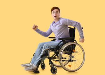 Young man in wheelchair on yellow background