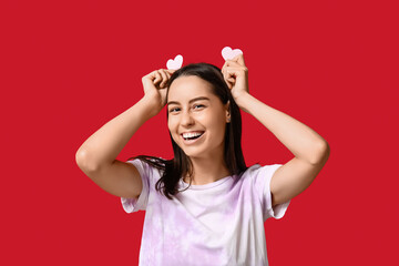 Funny young woman with paper hearts on red background