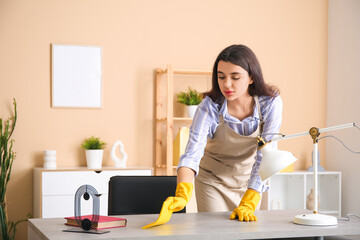 Young woman cleaning desk in living room