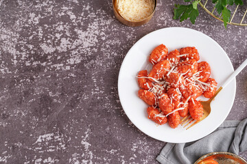 Plate of tasty gnocchi with cheese on grey background