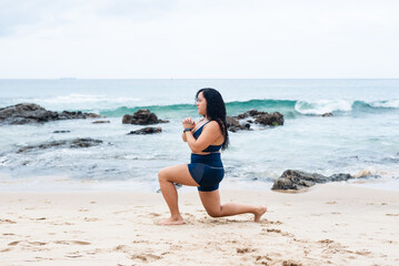 Portrait of beautiful fitness woman doing stretches on the beach sand.
