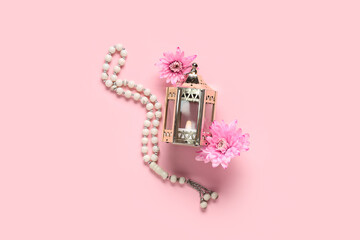 Muslim lamp with flowers and tasbih on pink background. Ramadan celebration