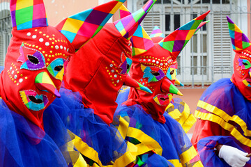 Three people dressed in colorful costumes and masks at the carnival parade