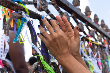 Fototapeta na wymiar Tourist hands tying souvenir ribbon on the iron railing of the Senhor do Bonfim church in the city of Salvador, Bahia.