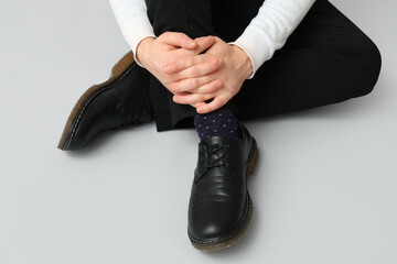 Young man in black elegant shoes on grey background