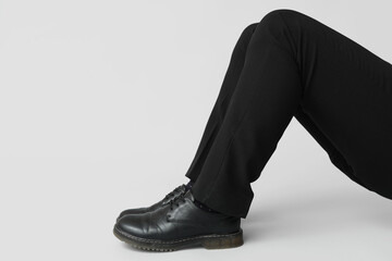 Legs of young man in black elegant shoes on grey background