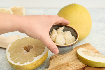 Female hand with bowl of fresh pomelo fruits on white background
