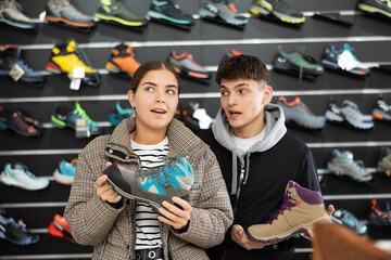 Experienced sales assistant helps guy buyer decide on choice of winter trecking cross-shoes, tells about advantages of product model, features of operation.