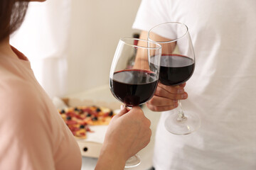 Couple clinking glasses of wine at home, closeup