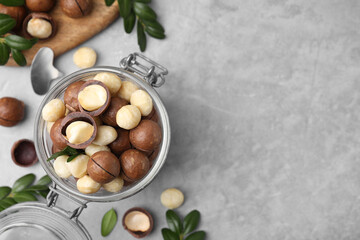Tasty Macadamia nuts in jar on light grey table, flat lay. Space for text