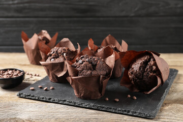 Delicious chocolate muffins on wooden table, closeup