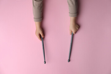 Little kid holding drumsticks on pink background, top view