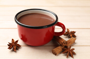 Tasty hot chocolate and spices on light wooden table, closeup