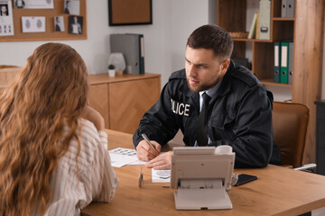 Male police officer working with victim in office