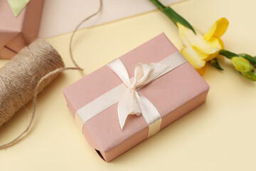Obraz na płótnie Canvas Gift box with beautiful flower and string on yellow background. International Women's Day