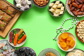 Frame made of different Eastern sweets and tasbih for Ramadan on green background