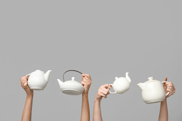 Women with ceramic teapots on grey background